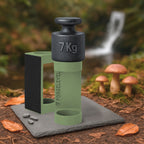 Schwarzes 7-Kilogramm-Gewicht auf olivem Halter mit der Aufschrift FORGELEVEL auf grauer Steinplatte im Wald mit Pilzen und Herbstlaub