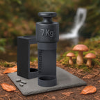 Schwarzes 7-Kilogramm-Gewicht auf schwarzem Halter mit der Aufschrift FORGELEVEL auf grauer Steinplatte im Wald mit Pilzen und Herbstlaub